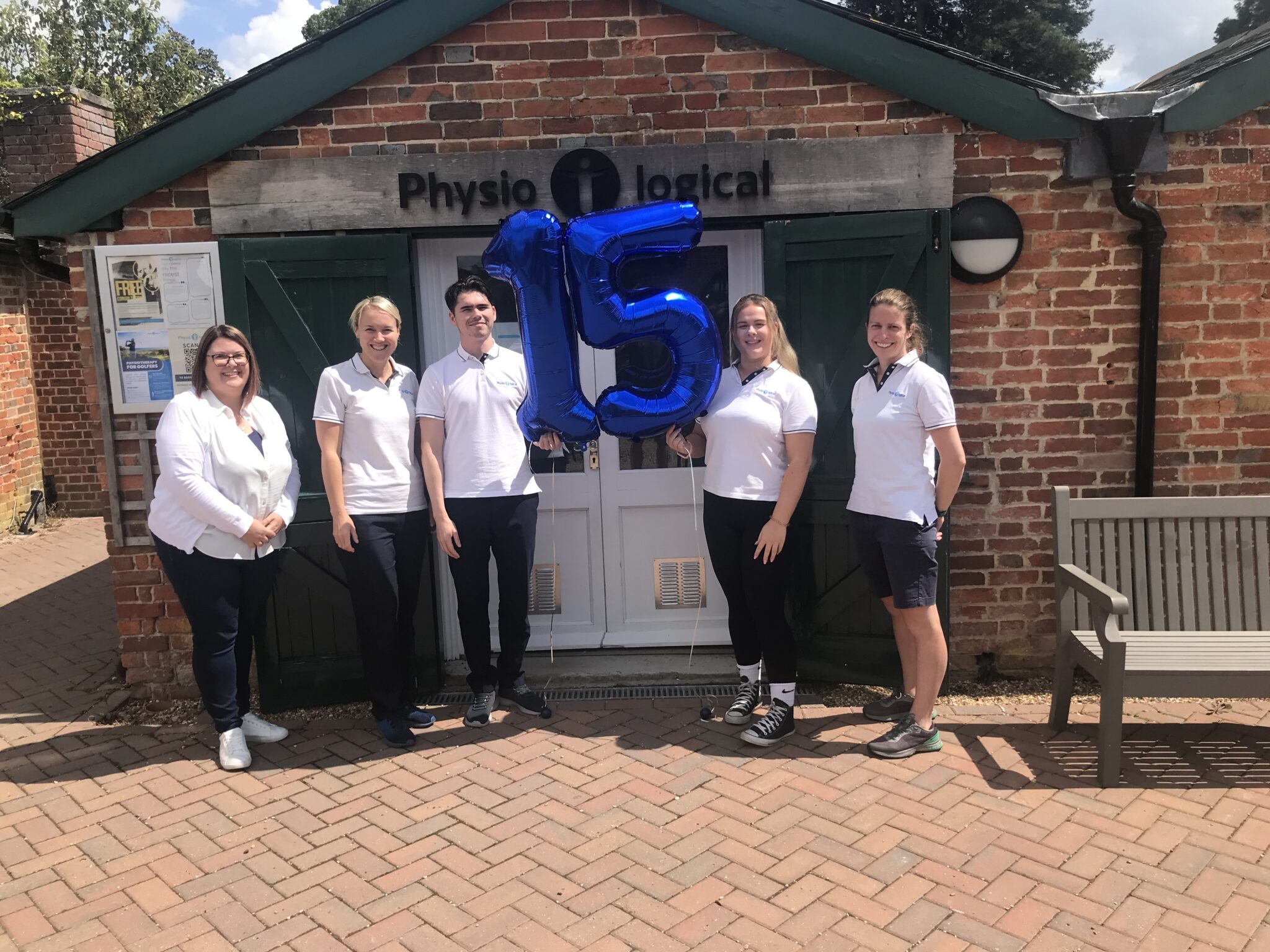 Physio-logical Team 15th Birthday photo with 15th birthday balloon outside Physio-logical clinic on stansted park estate